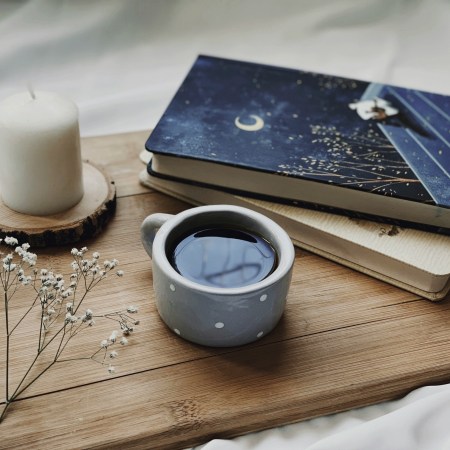a deck of oracle cards on a table, with a candle and a small pot of dark liquid